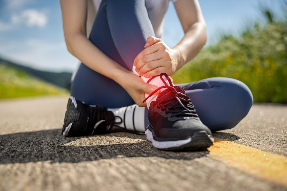 person running holding their ankle in pain